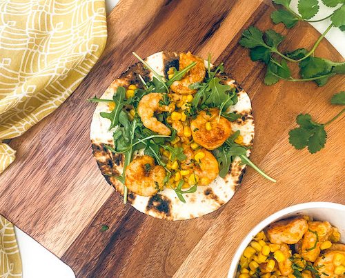Blackened shrimp and cilantro on a tortilla.