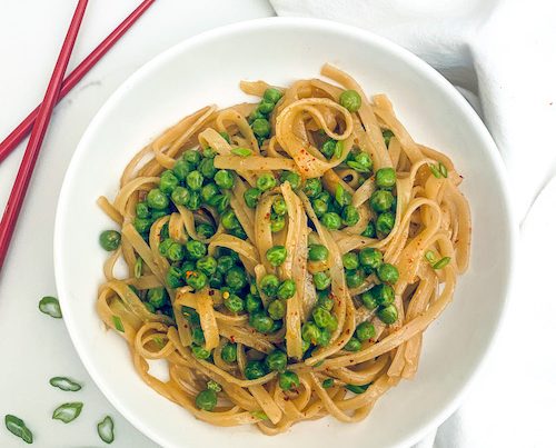 Garlic miso rice noodles in a bowl with peas.