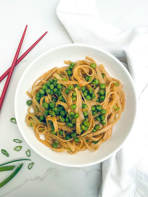 Garlic miso rice noodles in a bowl with peas.
