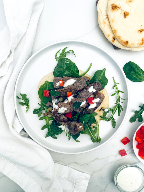 Greek style ribeye steak with spinach on a pita.