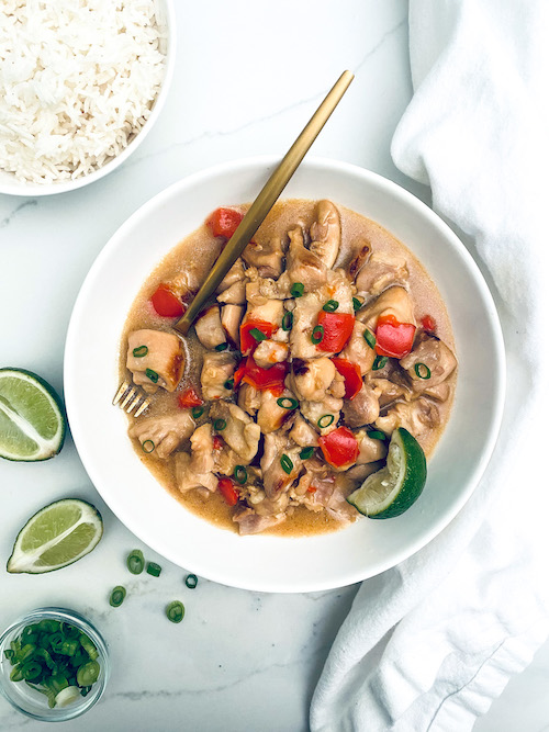 Hawaiian chicken and peppers in a white bowl with lime wedges.