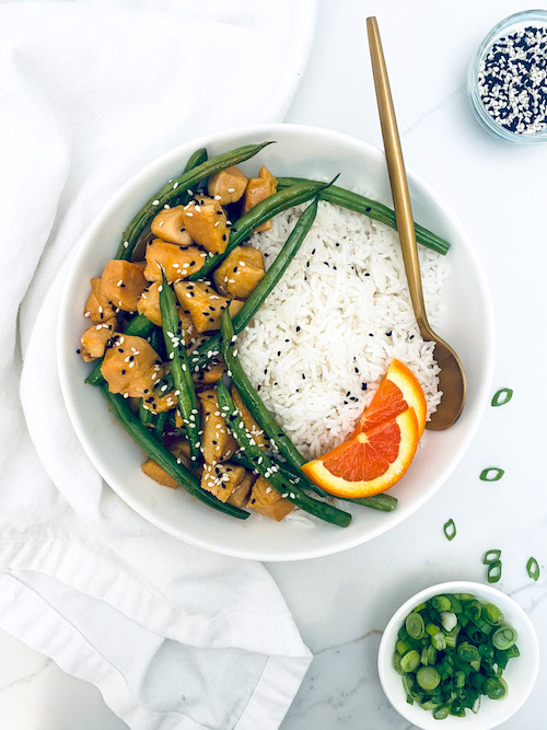 White rice next to honey orange chicken and green beans.