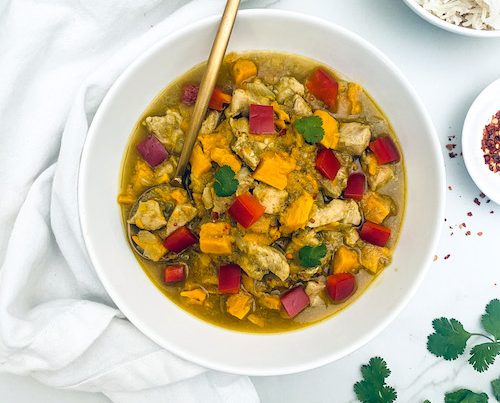 A white bowl of Thai curry chicken with sweet potatoes.