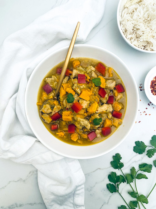 A white bowl of Thai curry chicken with sweet potatoes.