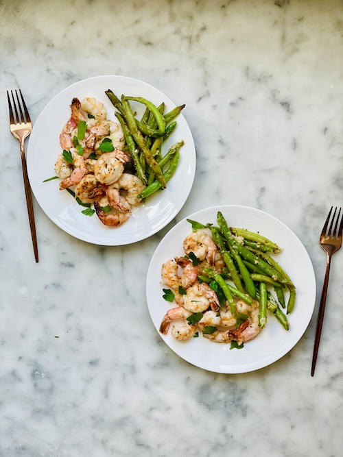 Parmesan crusted shrimp with green beans on white plates.