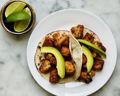 Cauliflower tempeh tacos served with avocado and lime.