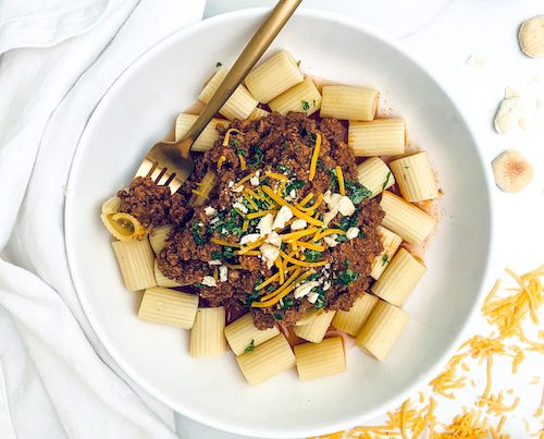 Cincinnati chili over rigatoni pasta in a white bowl.