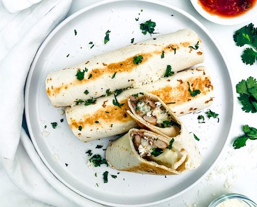 Black bean cheese taquitos on a white dinner plate.