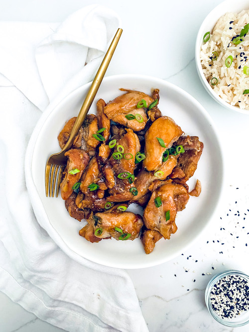 Korean chicken bulgogi on a white plate next to a bowl of rice.