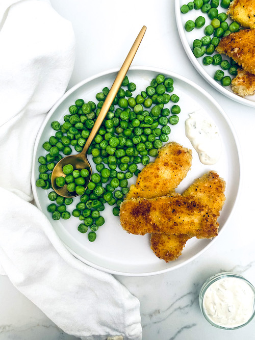 Lemon pepper fish sticks on a plate with peas.