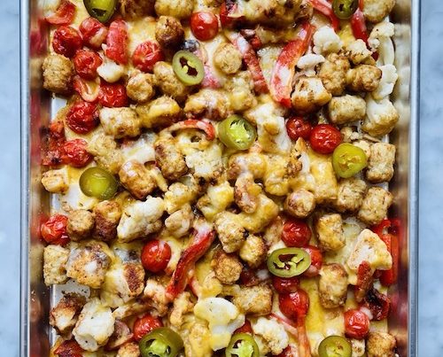 A sheet pan filled with baked tater tot nachos.