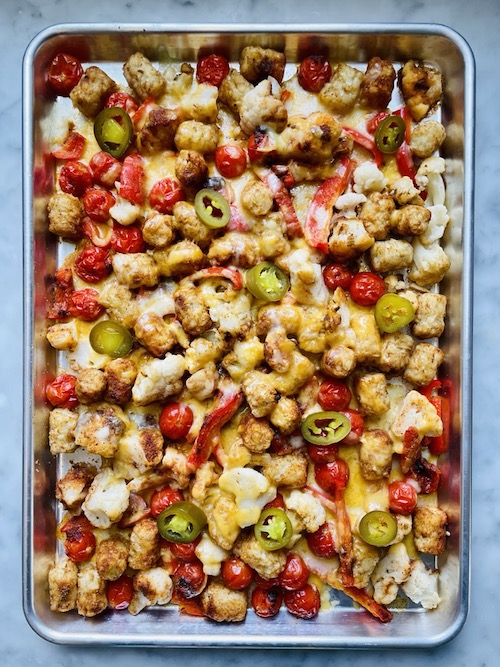A sheet pan filled with baked tater tot nachos.