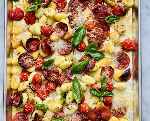 A sheet pan filled with baked gnocchi and pepperoni.