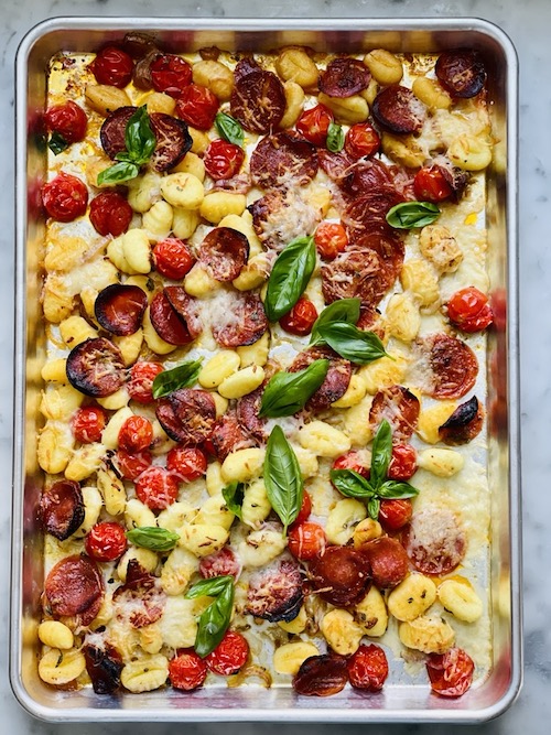 A sheet pan filled with baked gnocchi and pepperoni.