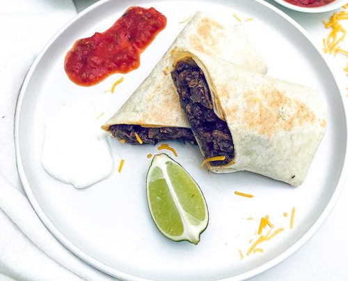 A beef and cheese burrito cut in half on a white dinner plate.
