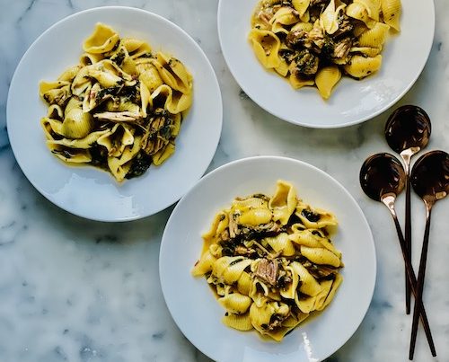 Three white bowls of cheddar shell pasta with pulled pork.