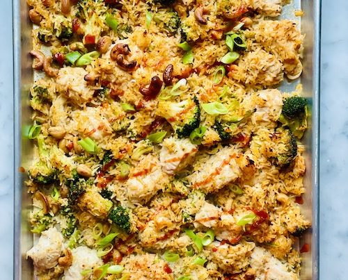Fried rice with chicken and broccoli on a parchment lined sheet pan.