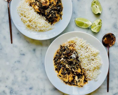 Green chicken curry with white rice in two white bowls.
