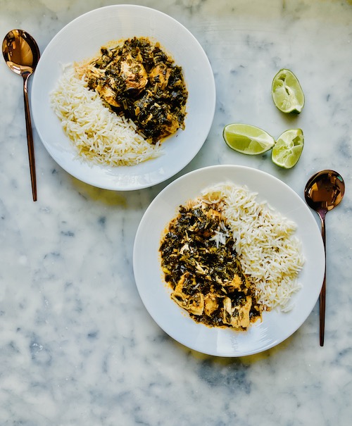 Green chicken curry with white rice in two white bowls.