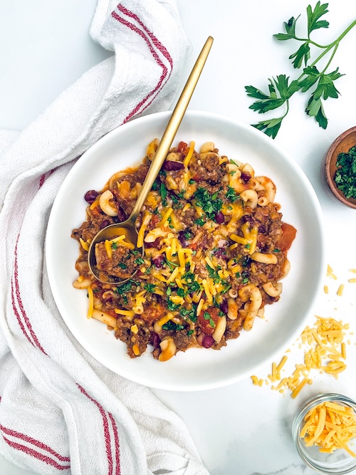 Chili Mac in a bowl topped with shredded cheese.