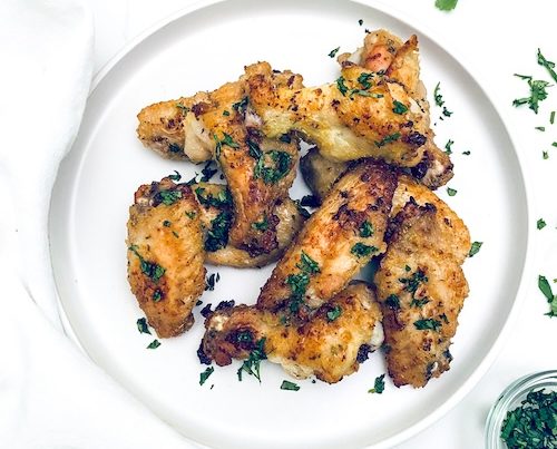 Citrus garlic chicken wings on a white plate.