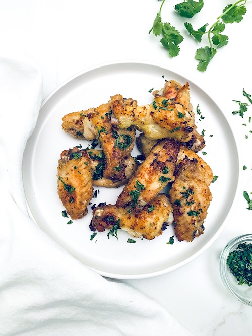 Citrus garlic chicken wings on a white plate.