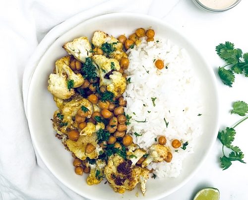 Roasted cauliflower and chickpeas with white rice on a dinner plate.