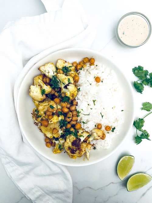 Roasted cauliflower and chickpeas with white rice on a dinner plate.