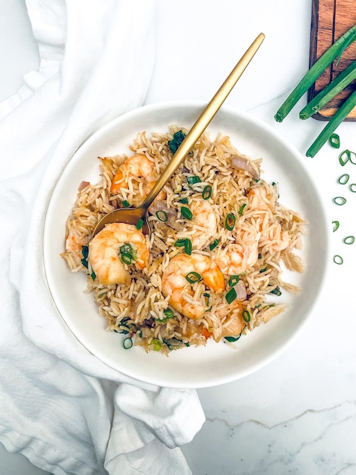 Thai seasoned shrimp over rice in a white bowl.