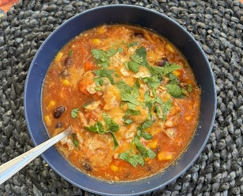 A bowl of chicken tortilla soup with a spoon.
