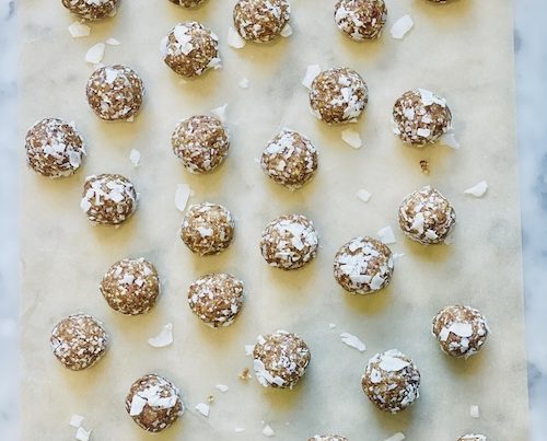 Coconut date energy balls on a sheet of parchment paper.