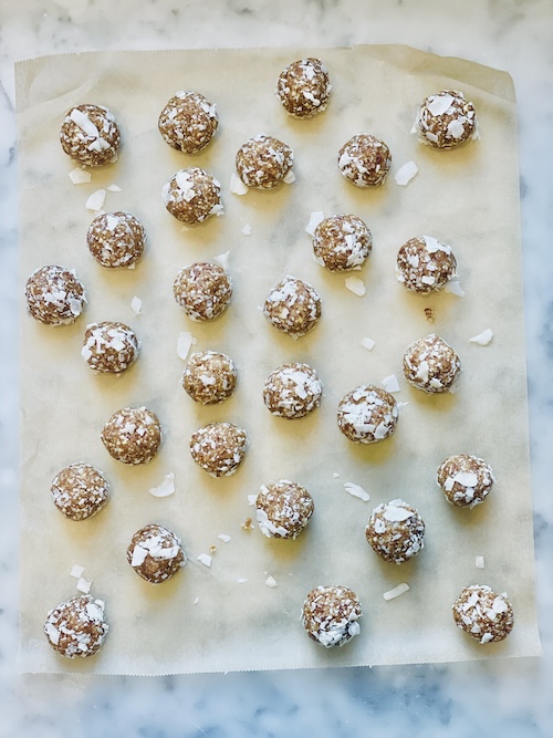 Coconut date energy balls on a sheet of parchment paper.