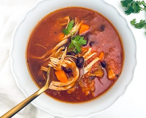 A white bowl of chicken enchilada soup.