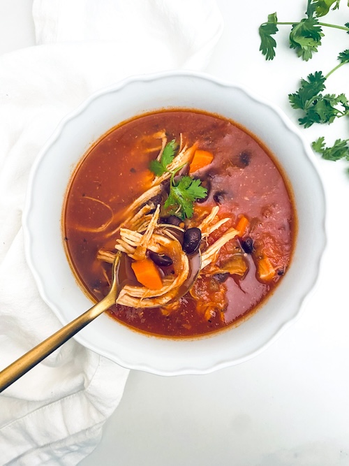 A white bowl of chicken enchilada soup.