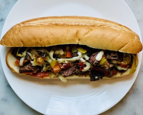 Italian beef with cheese and peppers on a roll.