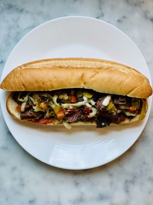 Italian beef with cheese and peppers on a roll.