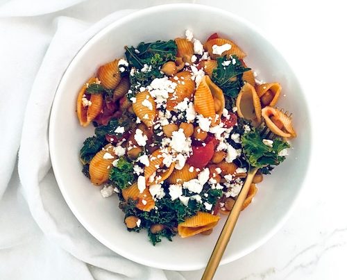 Chickpea kale pasta in a white bowl with a fork.