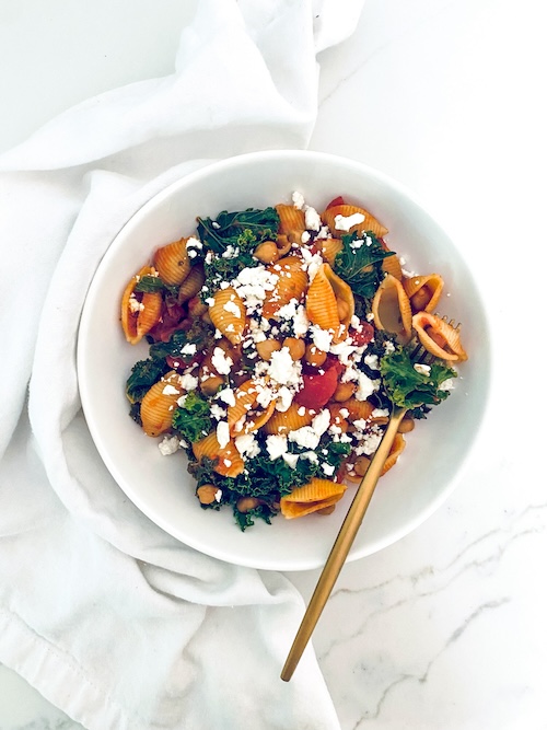 Chickpea kale pasta in a white bowl with a fork.