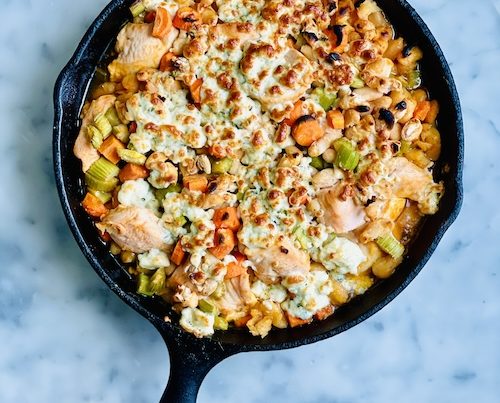 A cast iron skillet filled with buffalo chicken and veggies.