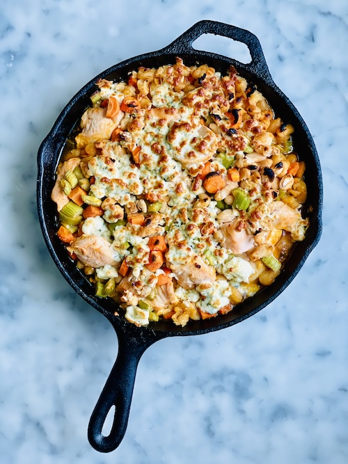 A cast iron skillet filled with buffalo chicken and veggies.