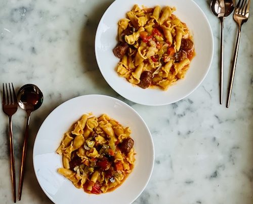 Sausage and pepper pasta in two white bowls.