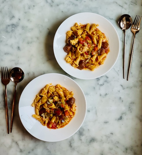 Sausage and pepper pasta in two white bowls.