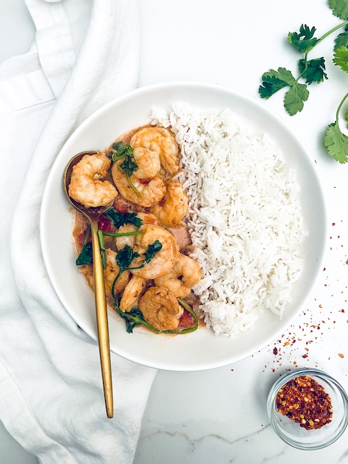 Indian butter shrimp and rice on a white plate.