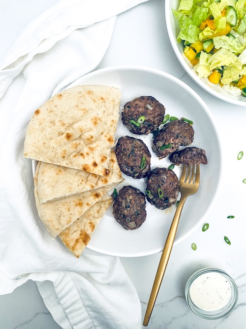 Moroccan meatballs and pita on a white plate.