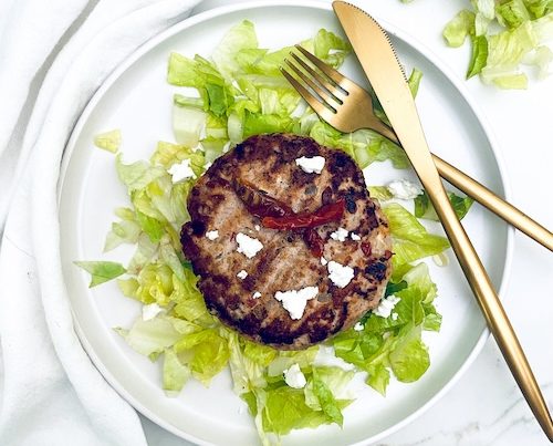 Sundried tomato feta turkey burger on a bed of lettuce.