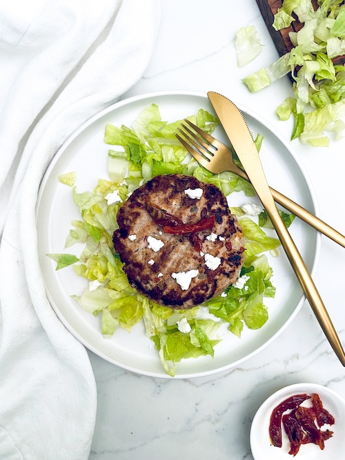 Sundried tomato feta turkey burger on a bed of lettuce.