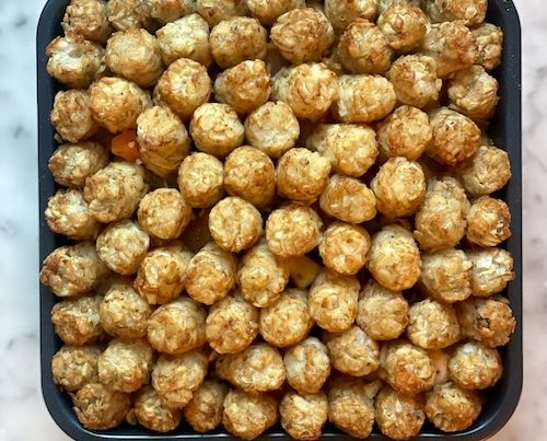 Tater tot casserole in a square baking dish.