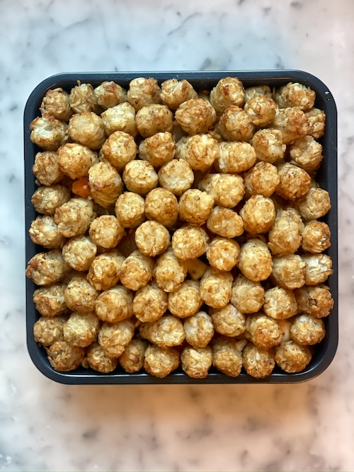 Tater tot casserole in a square baking dish.