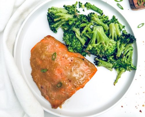 Honey glazed salmon and broccoli on a plate.