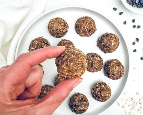 A hand holding a chocolate chip energy bite.